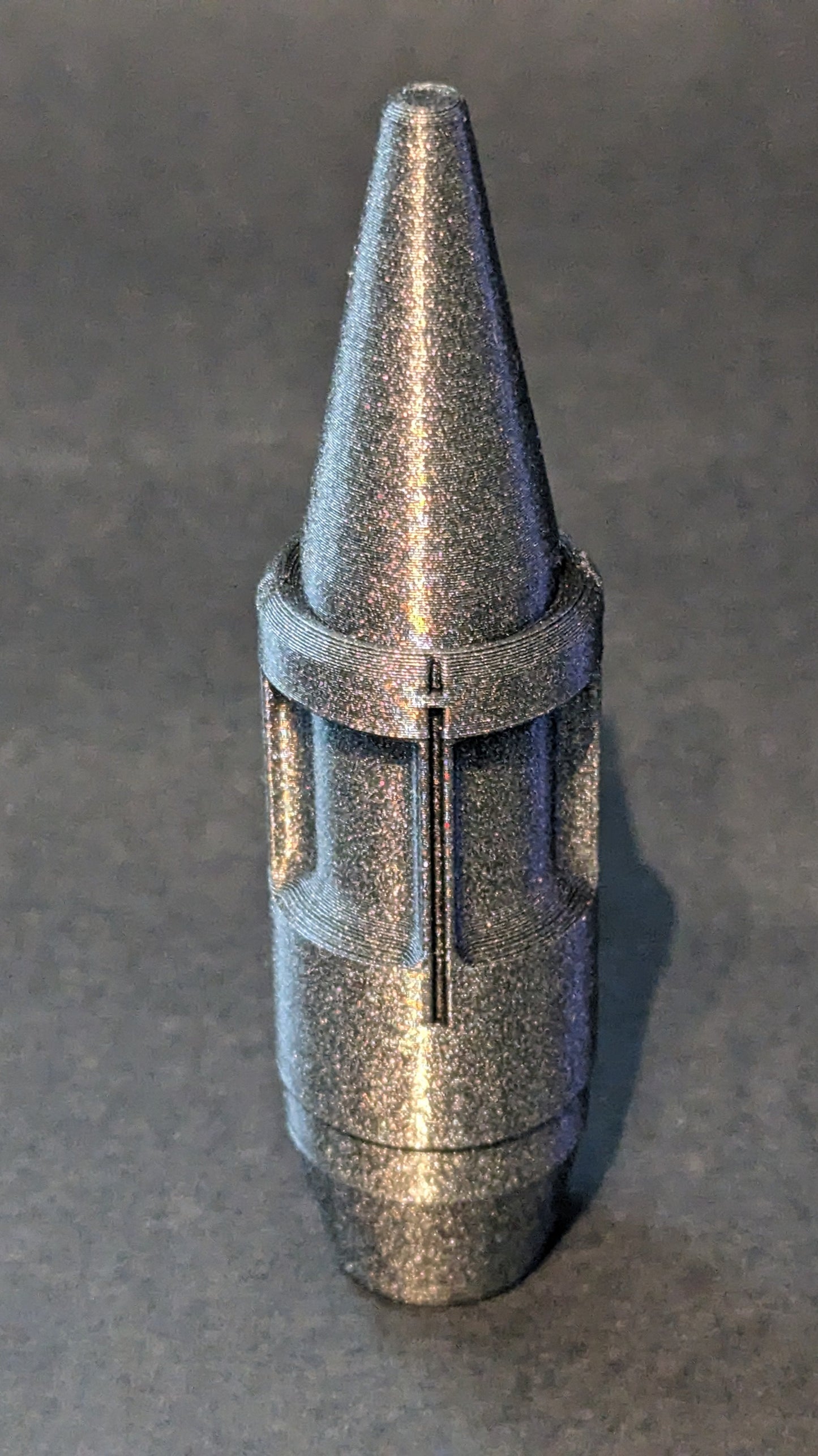 Metallic cone-shaped object on a gray background