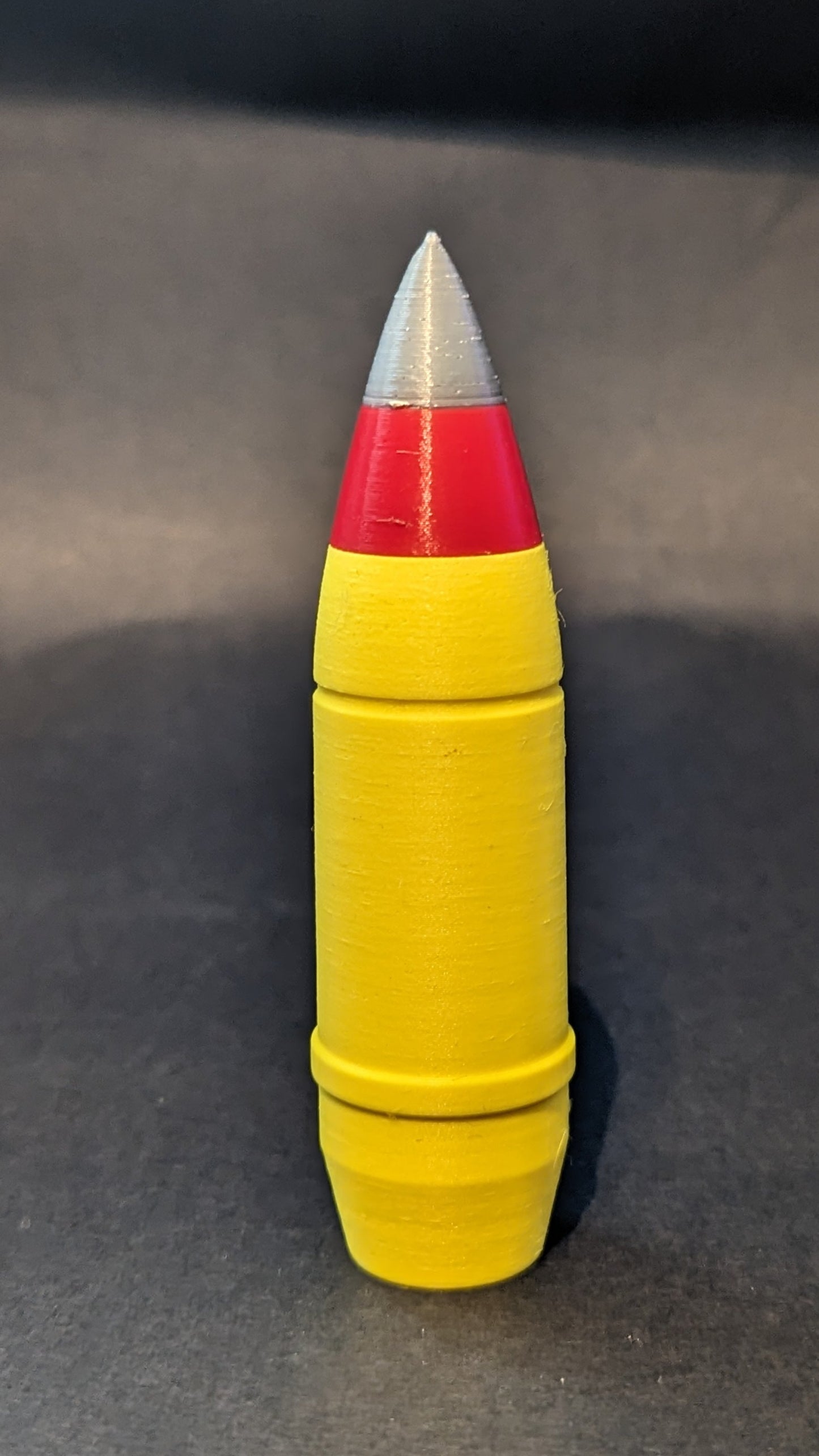Yellow cylindrical object with red and silver top on a gray background