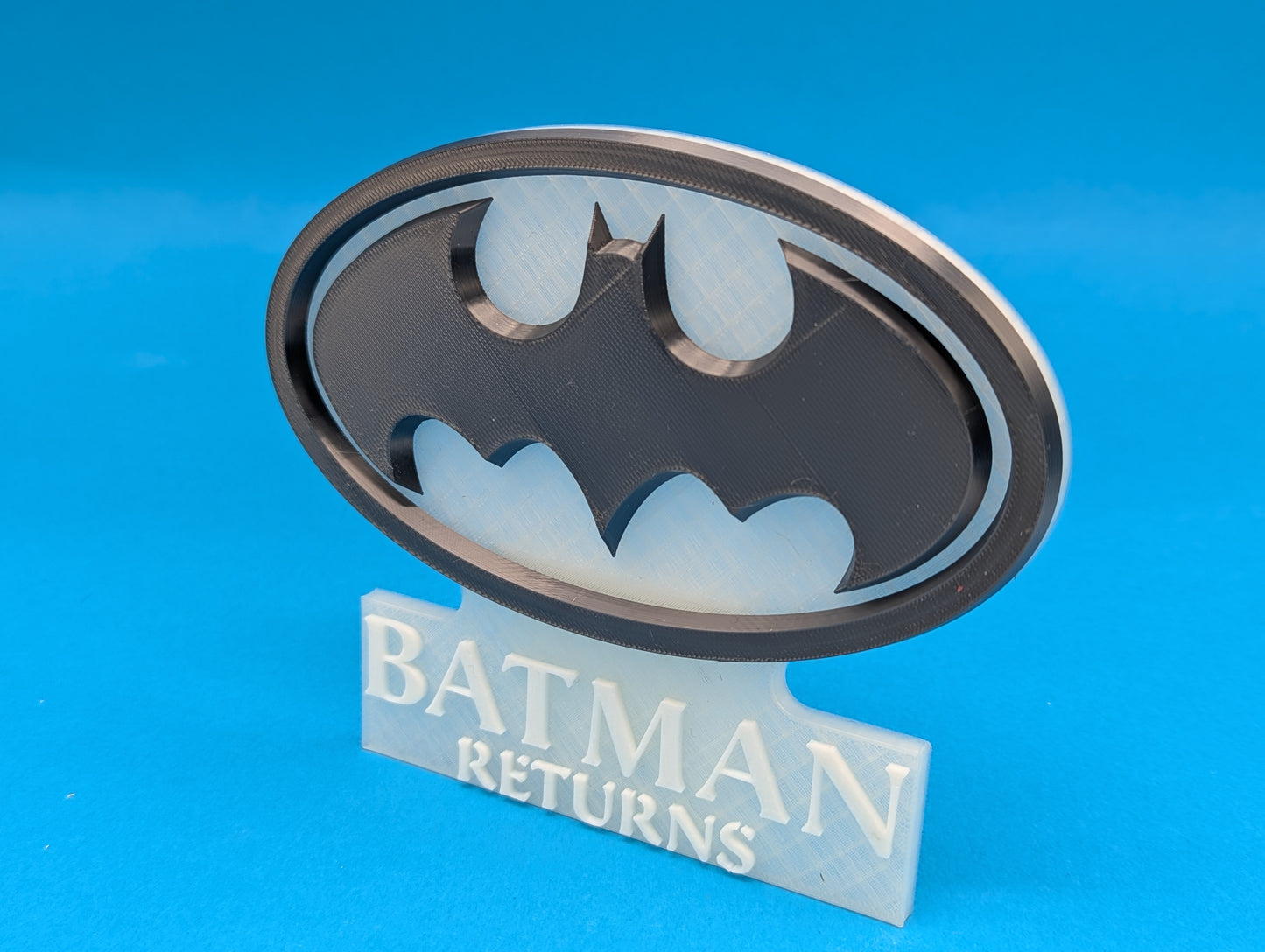 Batman logo with 'Batman Returns' text on a blue background