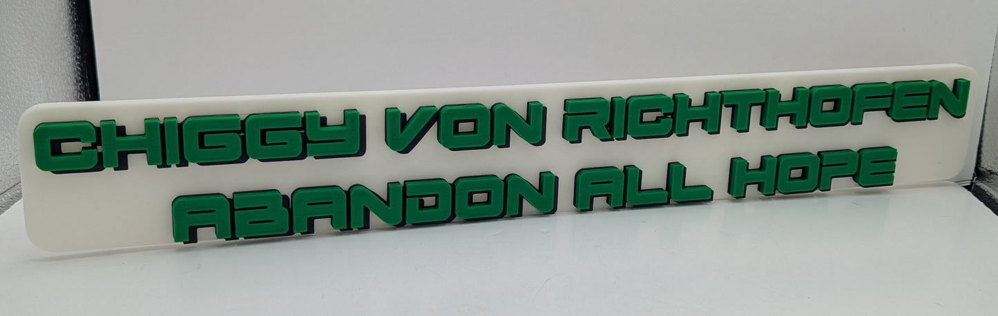 White sign with green text 'CHIGGY VON RICHTHOFEN ABANDON ALL HOPE' on a white background