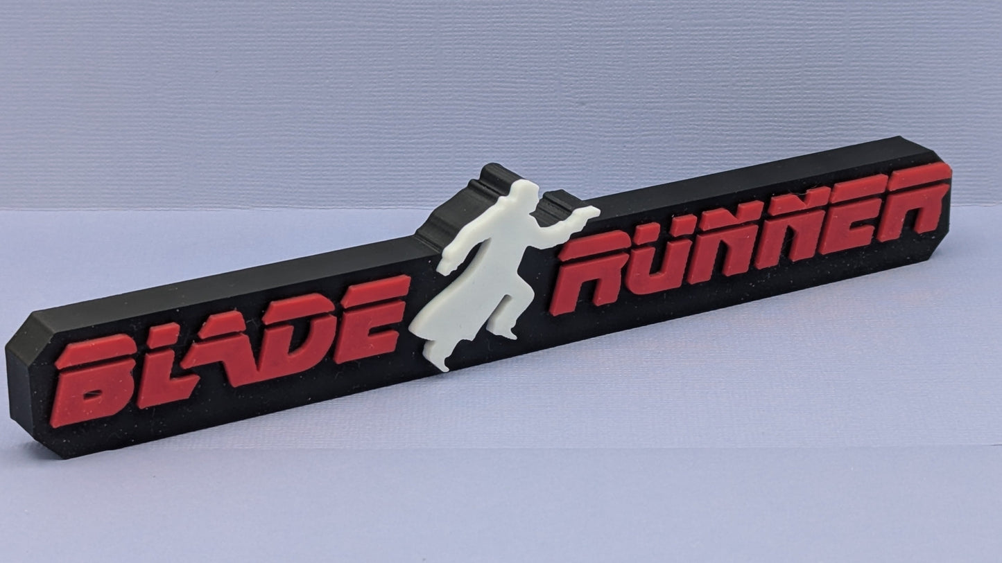 Blade Runner logo on a black rectangular block with a white silhouette of a person.