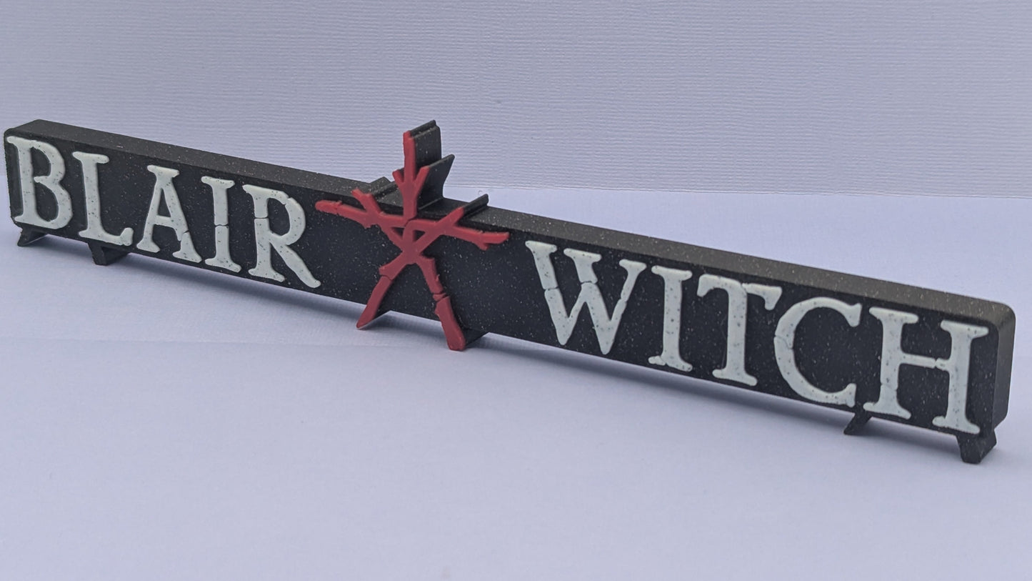 Wooden sign with 'Blair Witch' text and red star on a gray background