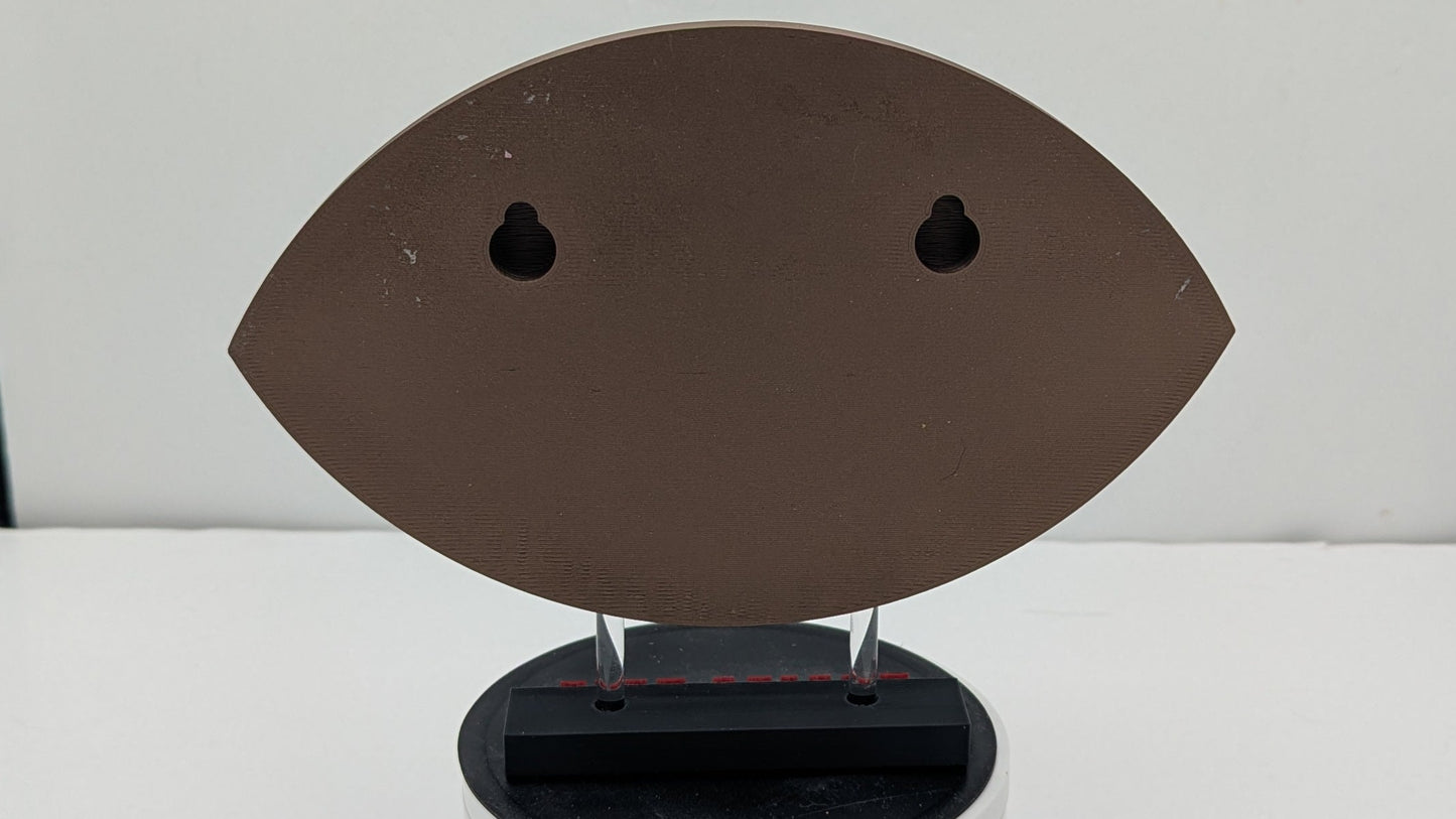 Brown and black object resembling a face on a white platform with a white background