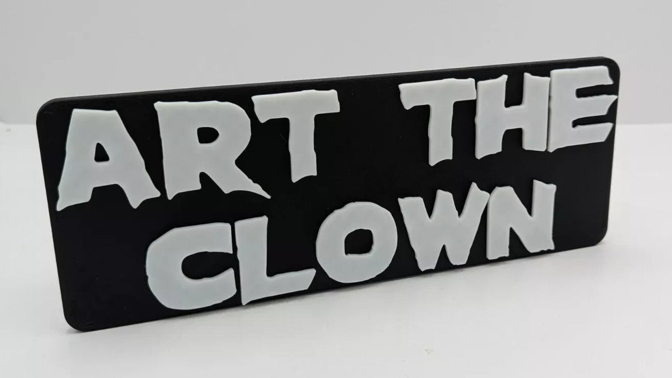 Black sign with white text 'ART THE CLOWN' on a light gray background