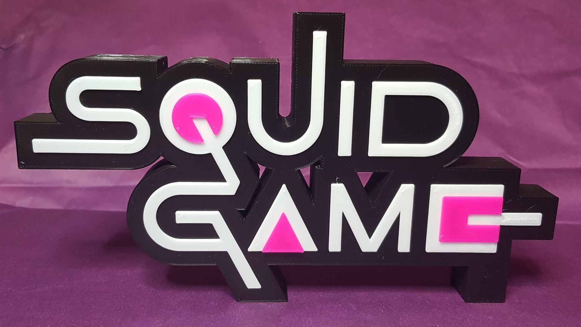 Sculpted 'Squid Game' logo on a purple background