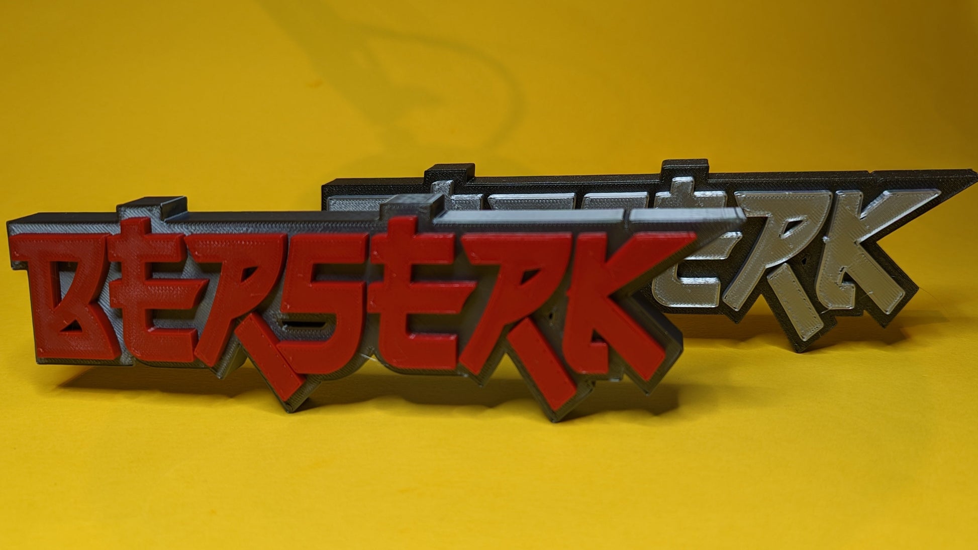 3D-printed 'Berserk' logo on a yellow background