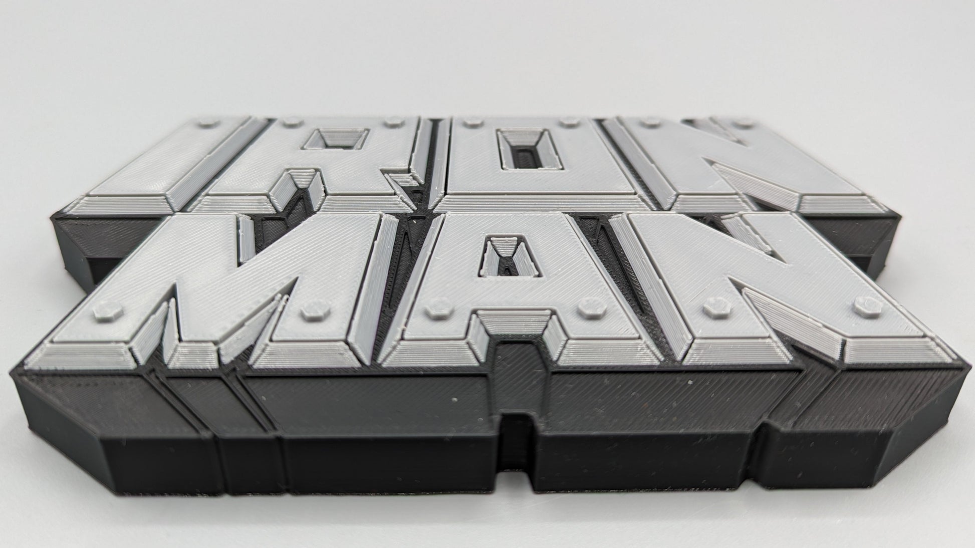 Metallic 'Iron Man' logo on a reflective surface