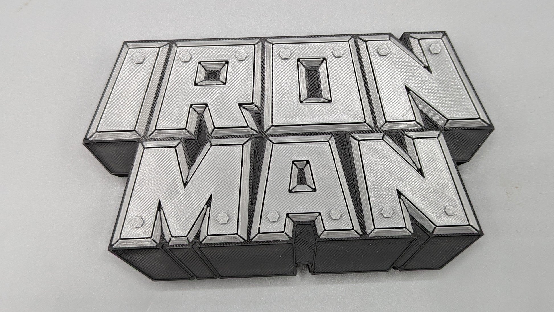 Metallic 'Iron Man' logo on a gray background