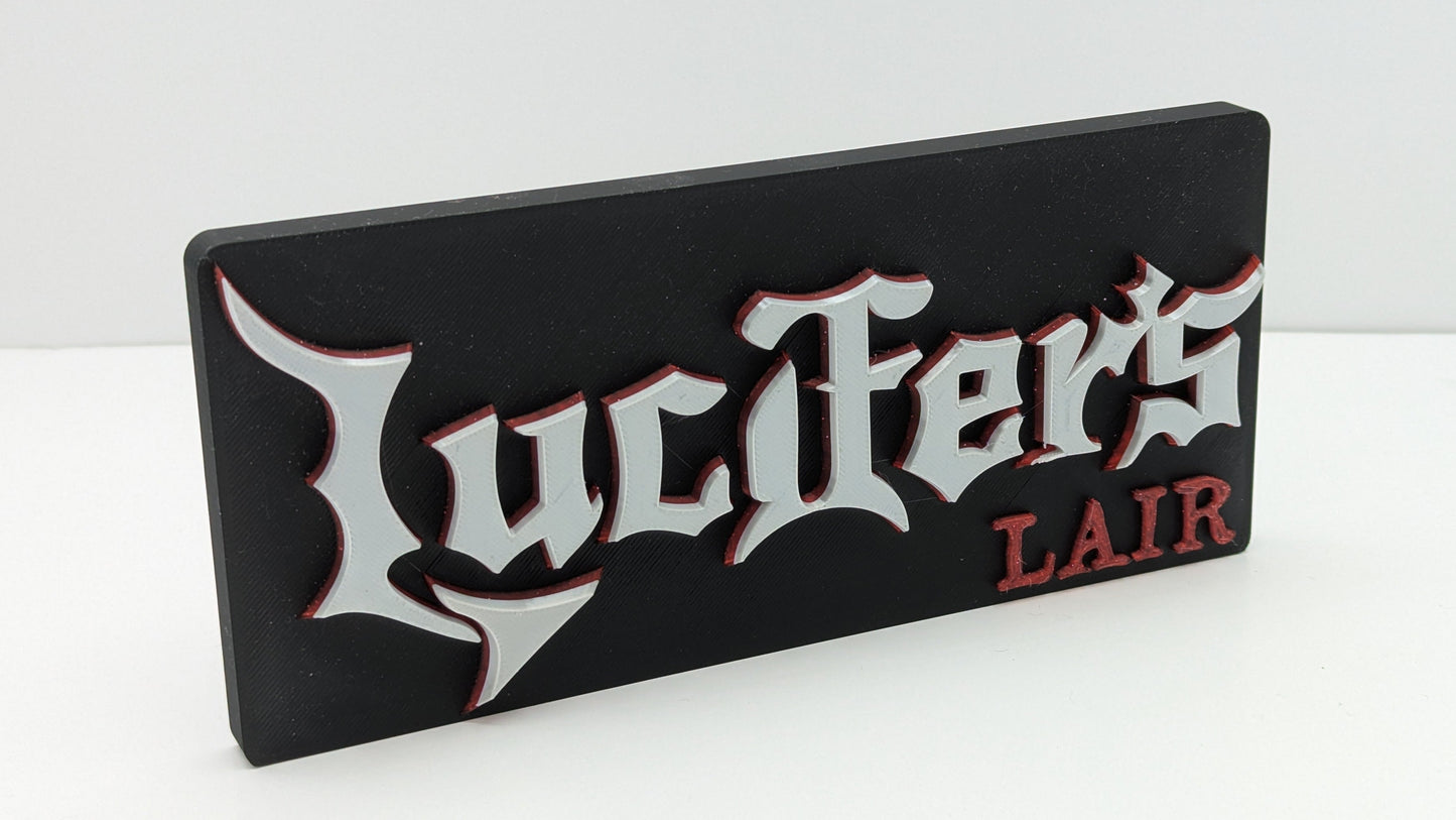 Decorative sign with 'Lucifer's Lair' text on a white background