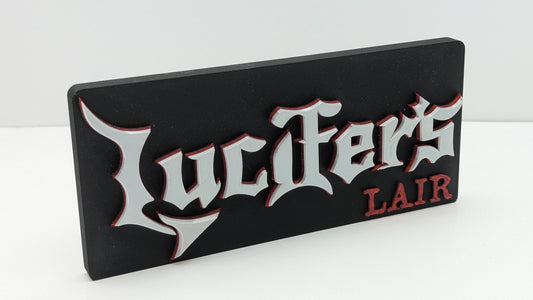 Decorative sign with 'Lucifer's Lair' text on a white background