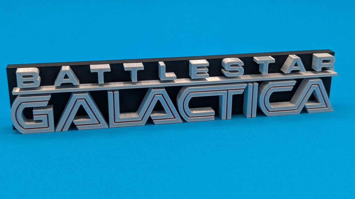 Metallic 'Battleteast Galactica' emblem on a blue background