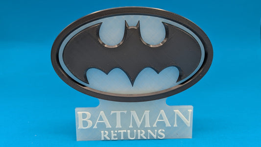 Batman logo with 'Batman Returns' text on a blue background