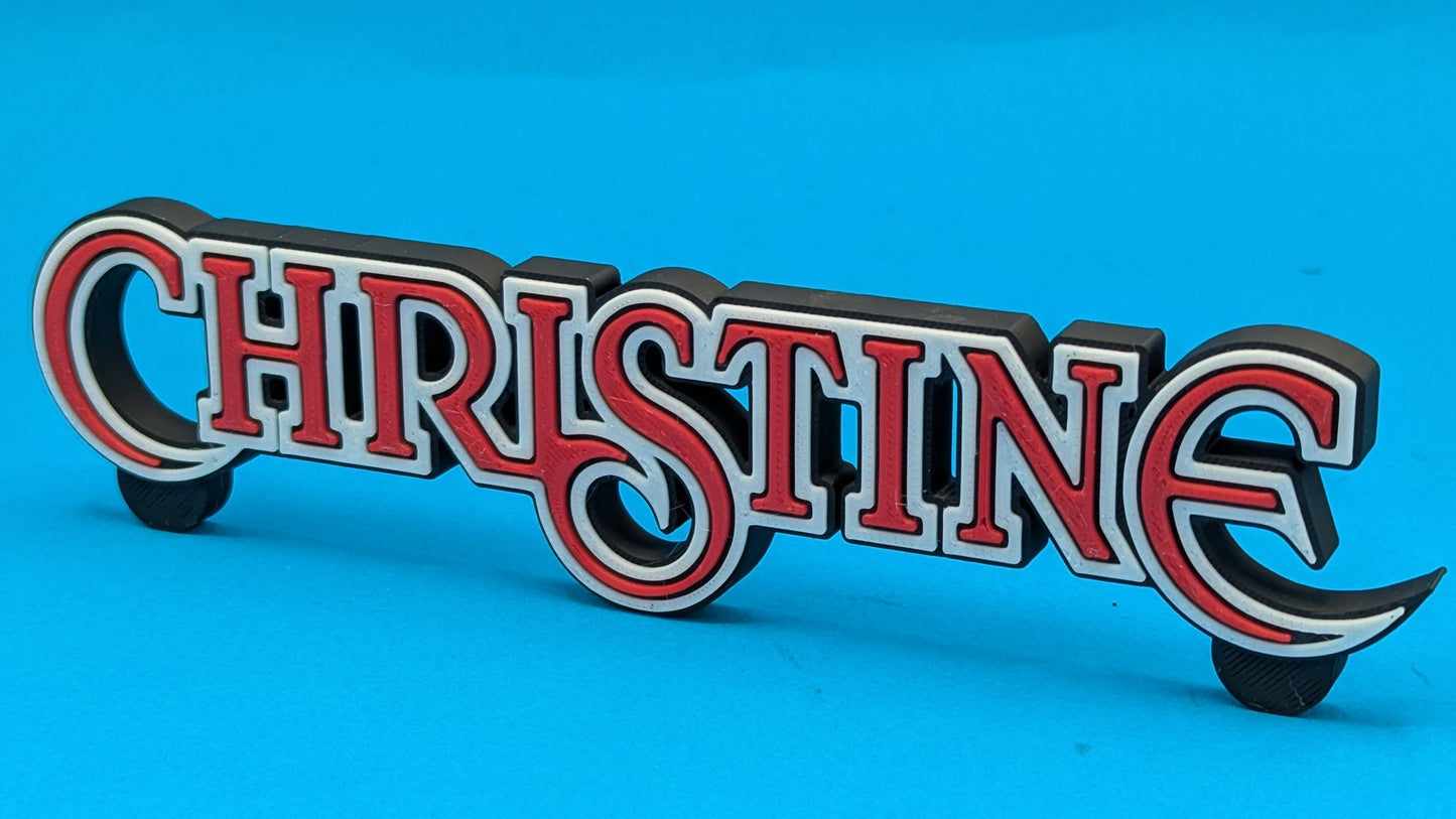 Wooden sign with 'CHRISTINE' in red and white on a blue background