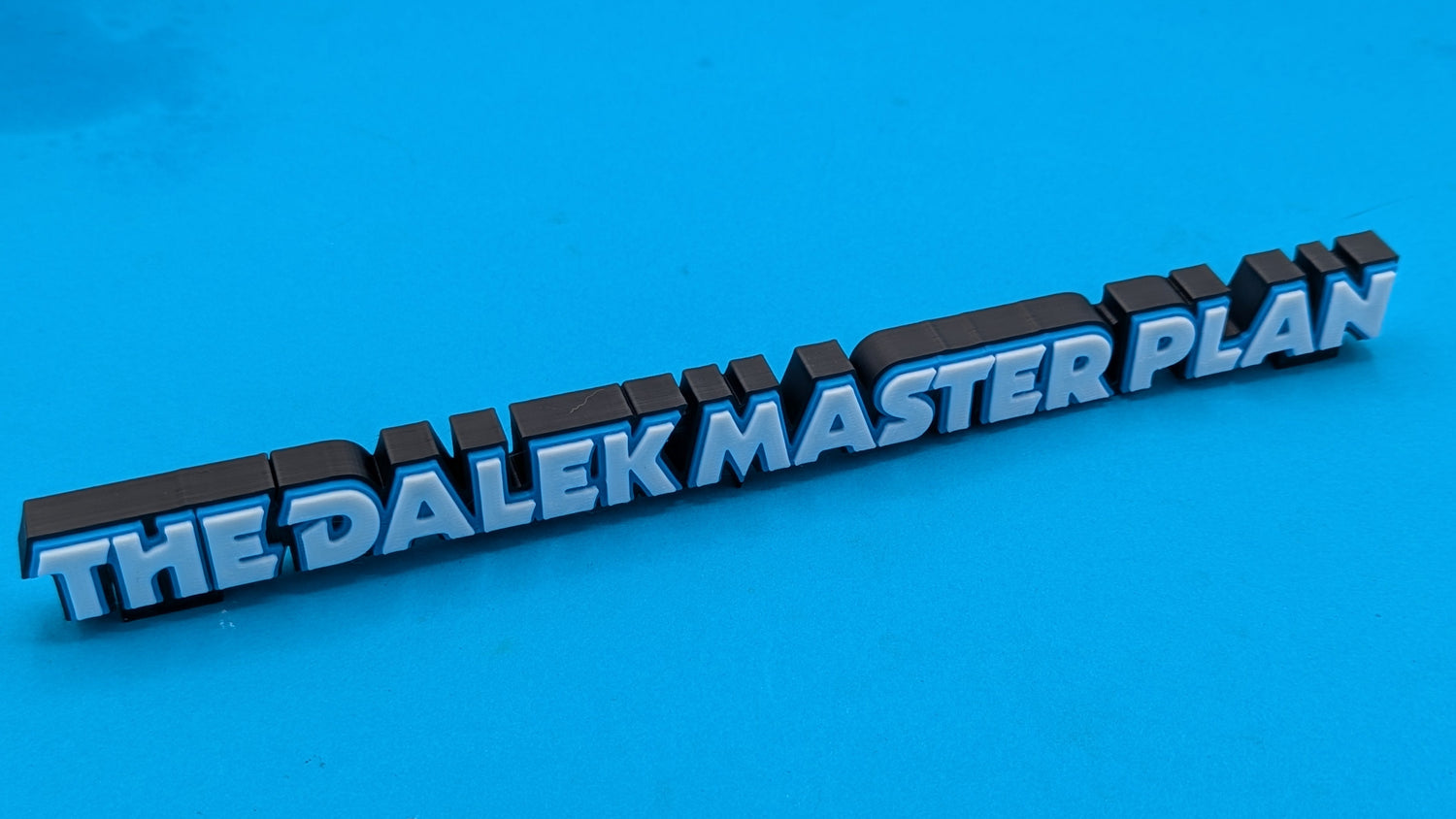 3D text 'THE DALEK MASTER PLAN' on a blue background