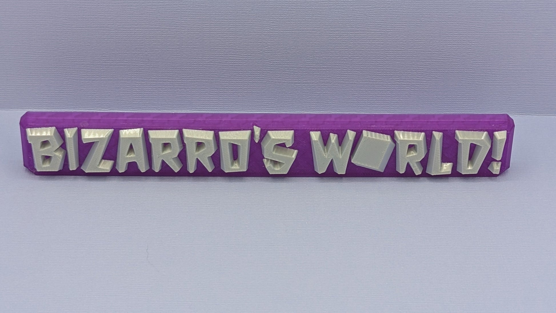 Purple rectangular object with 'BIZARRO'S WORLD!' text on a gray background