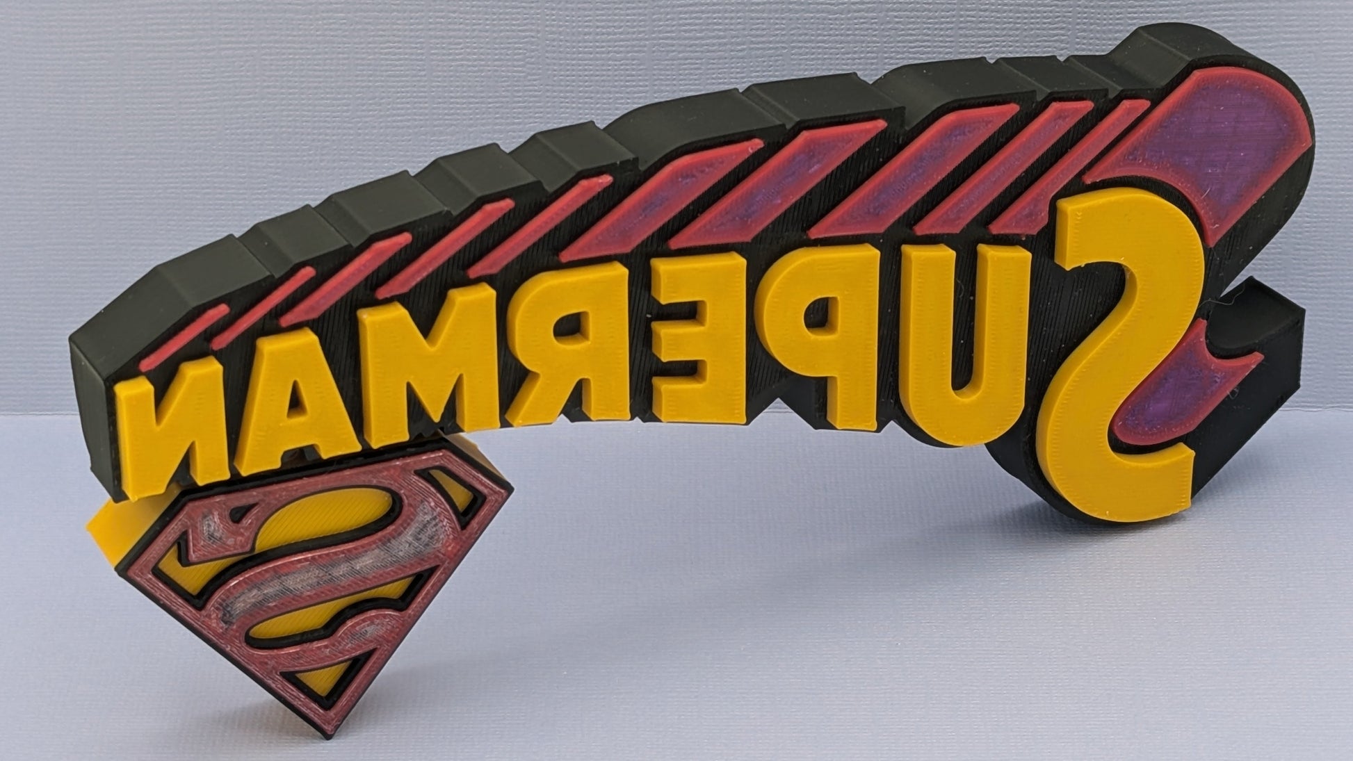 3D Superman logo with 'Superman' text on a gray background