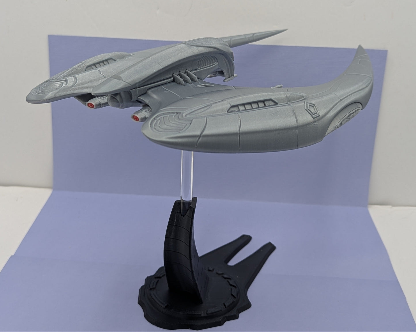 Model of a spaceship on a stand against a plain background