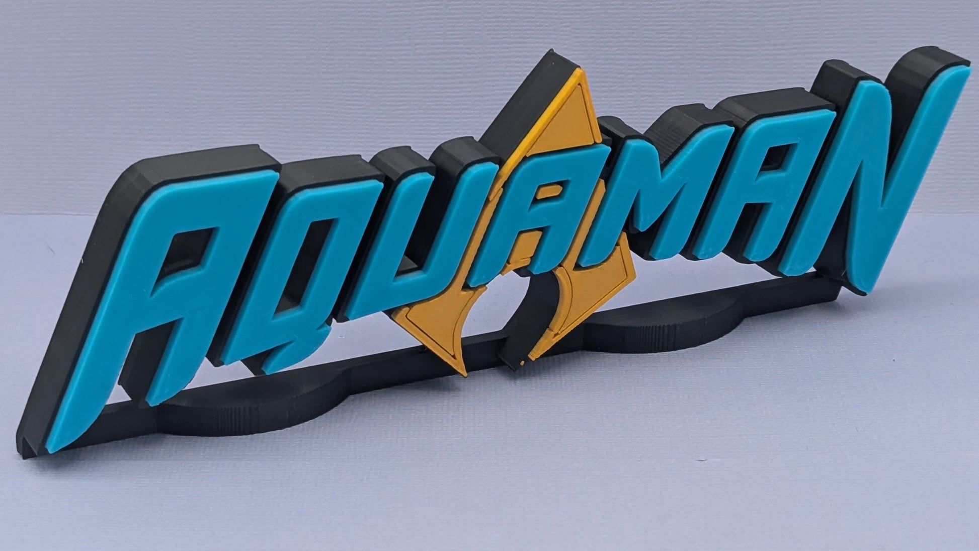 3D logo of 'Aquaman' with blue and black text on a gray background