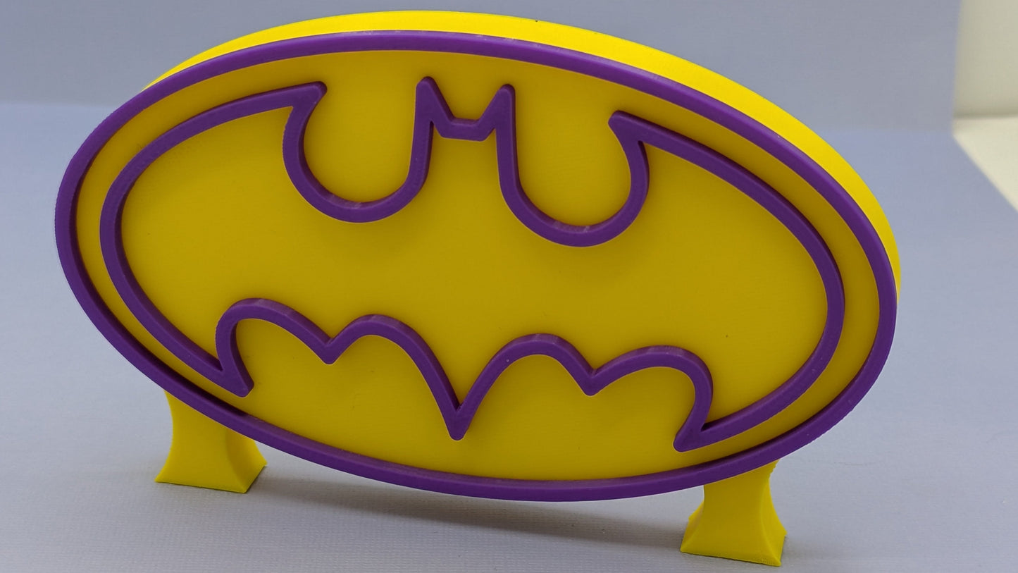 Yellow and purple Batgirl logo on a gray background