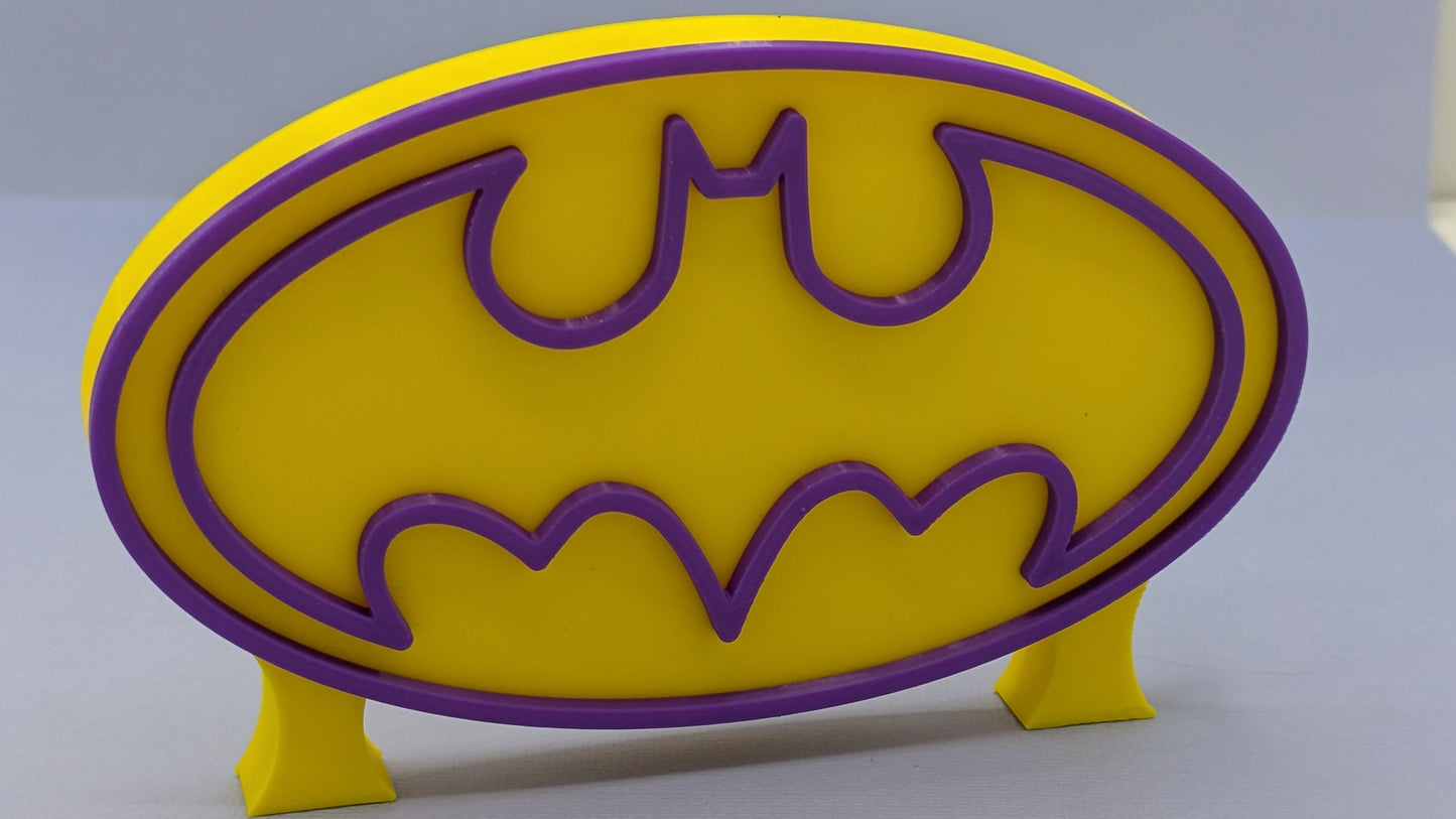 Yellow and purple Batgirl logo on a gray background