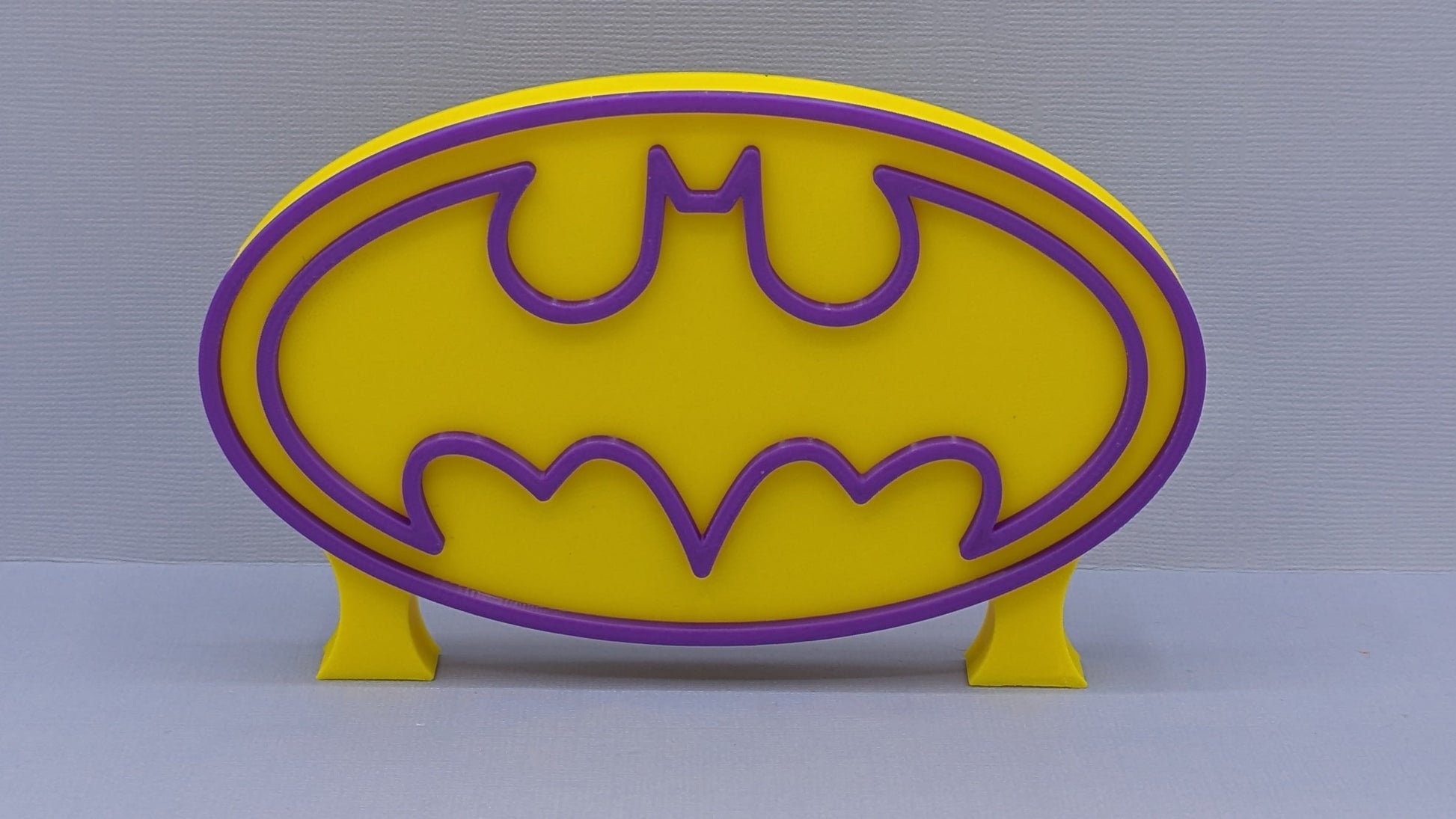 Yellow and purple bat symbol on a gray background