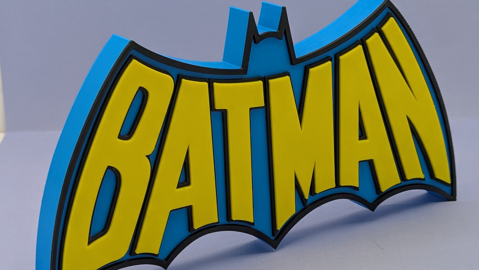 Batman logo with blue and yellow colors on a gray background