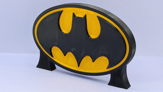Batman logo on a black stand against a light blue background
