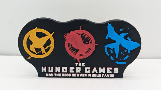 Decorative item with 'The Hunger Games' logo and text on a white background