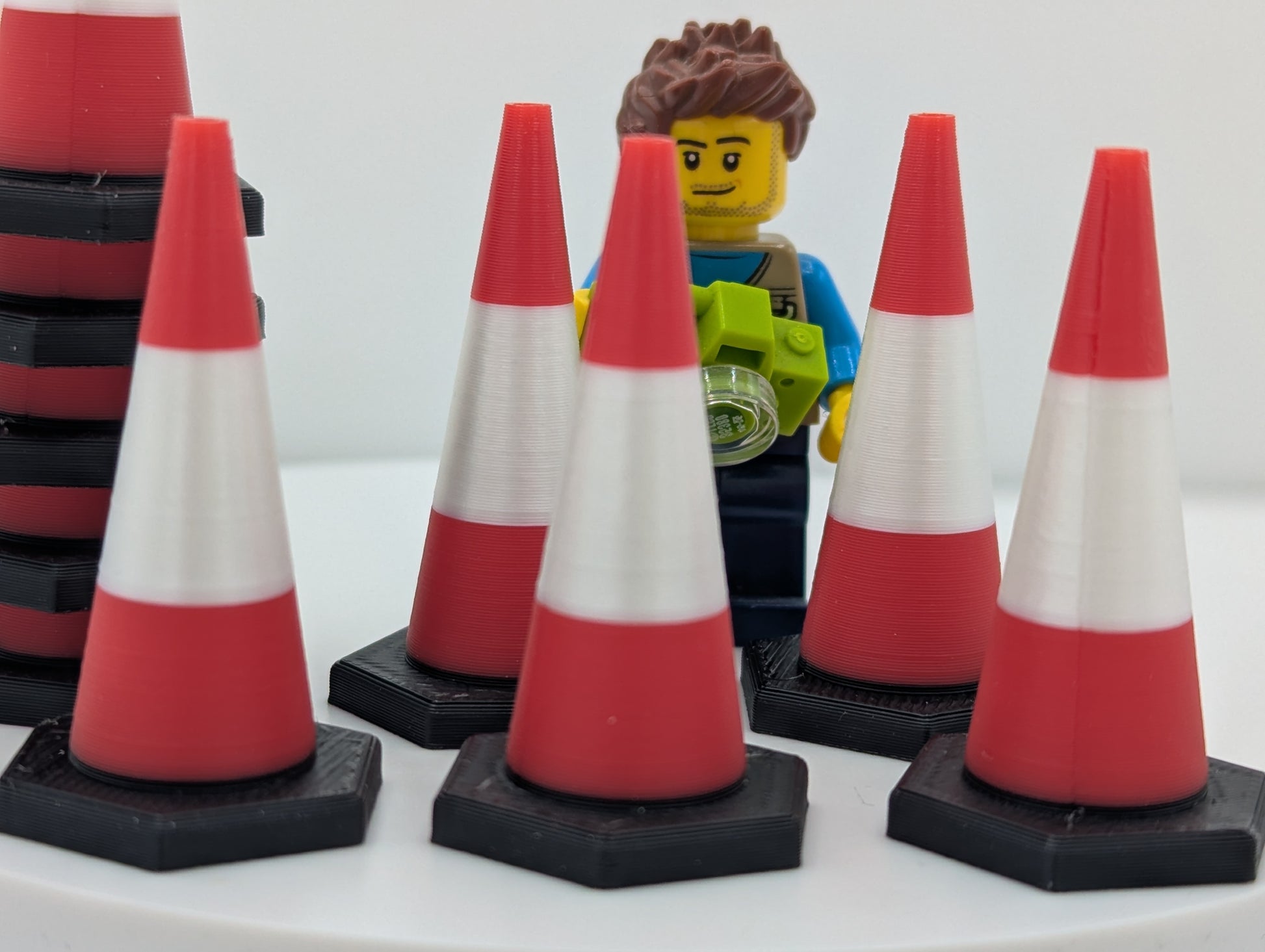 LEGO figure with red and white traffic cones on a white background