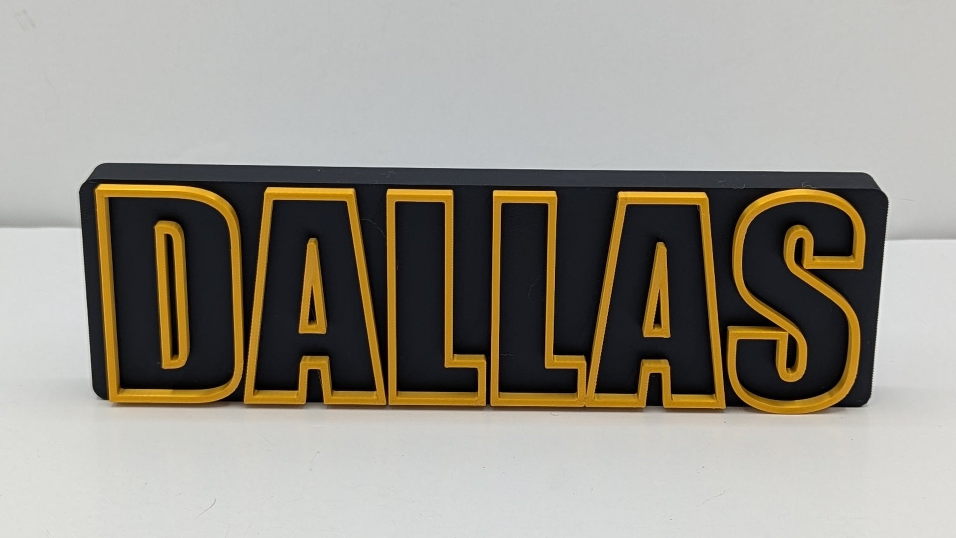 Black and gold 'DALLAS' sign on a white background