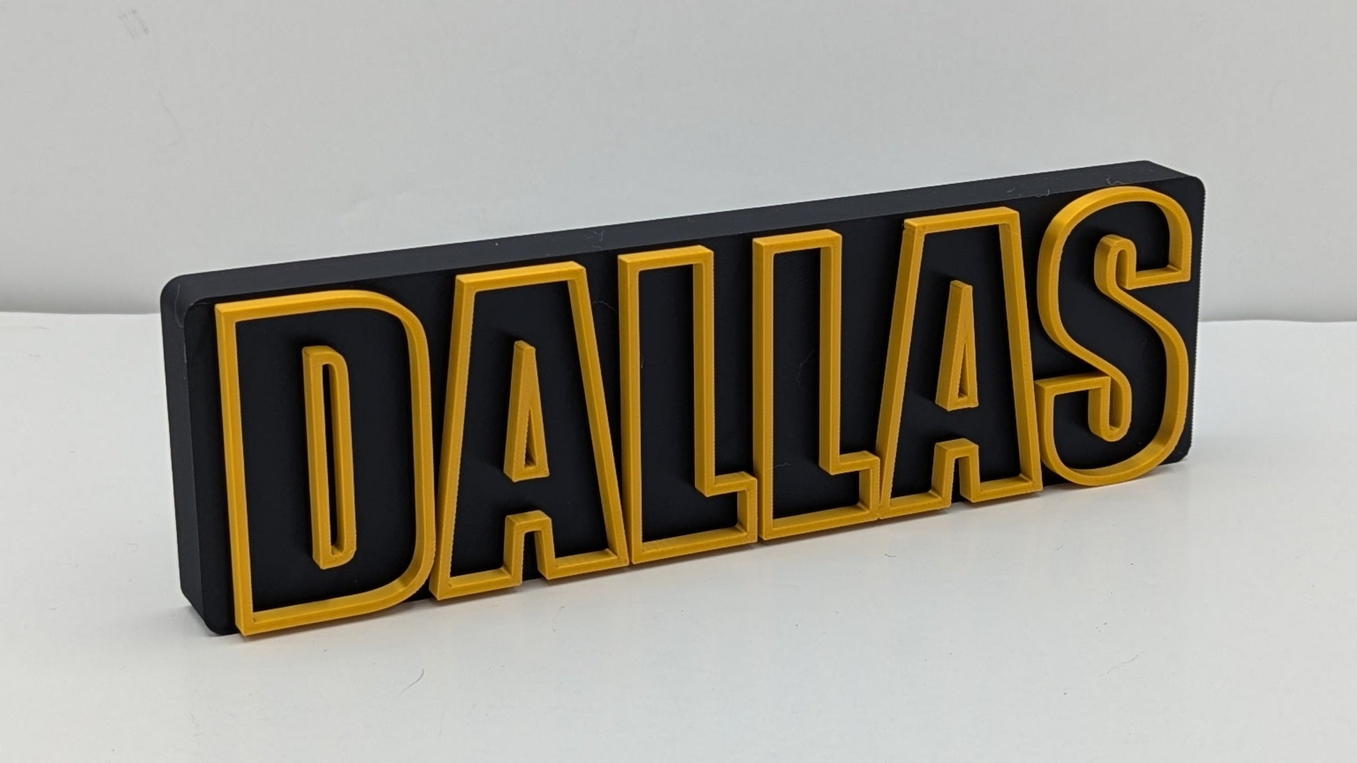 3D-printed 'DALLAS' letter block on a white background