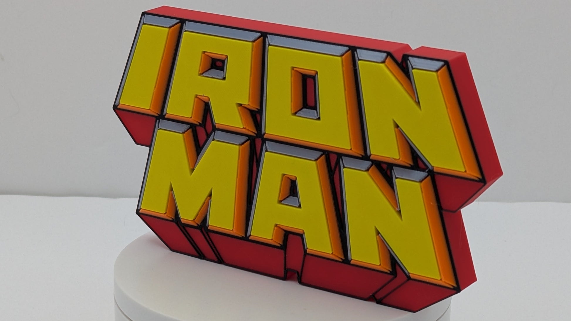 3D 'IRON MAN' logo on a white base with a gray background