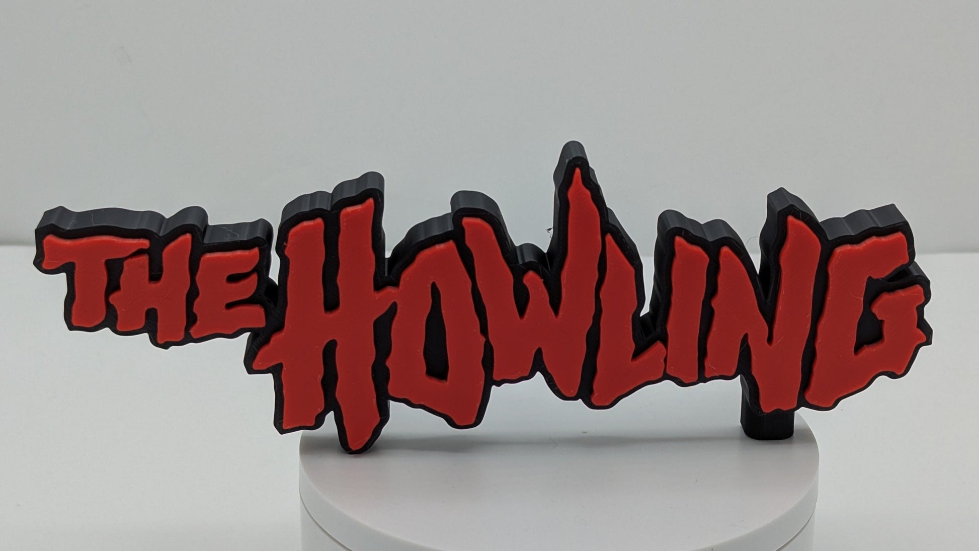 Decorative sign with 'The Howling' text on a white base against a gray background