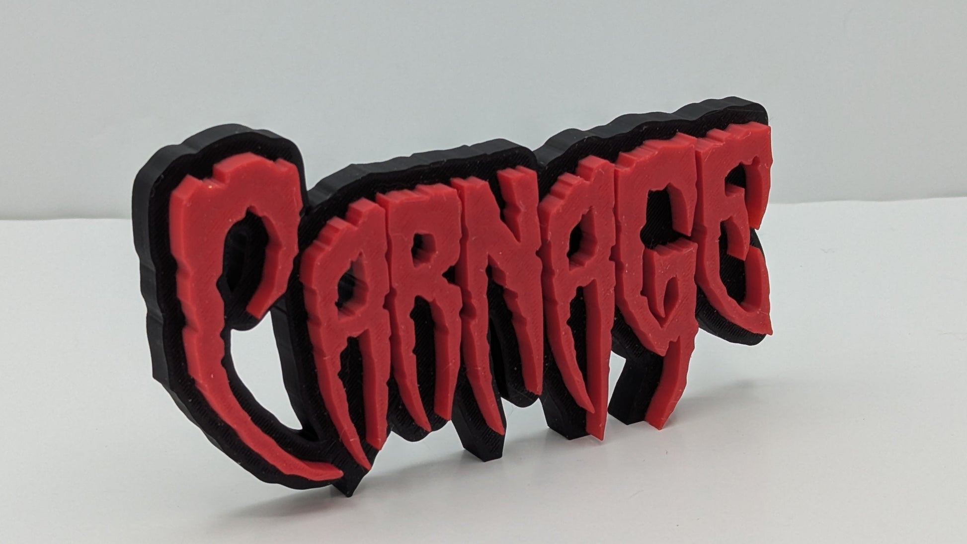 3D-printed 'Carnage' text in red and black on a white background
