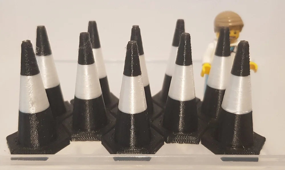 Set of 3D-printed traffic cones with a small figure on a white background